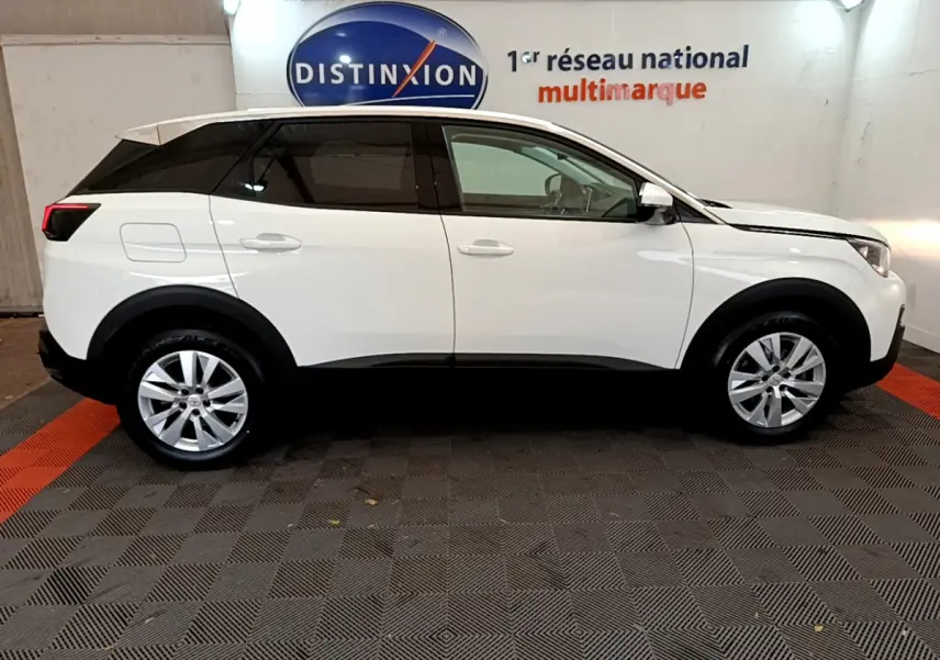 Profil côté gauche d’un SUV Peugeot 3008 blanc avec toit noir, dans un showroom au sol damier gris et rouge.