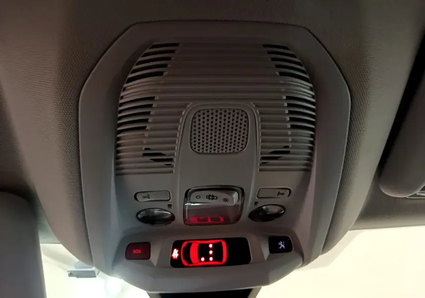 Vue en gros plan du plafonnier intérieur gris avec boutons de contrôle et témoin rouge allumé dans un Peugeot 3008 blanc