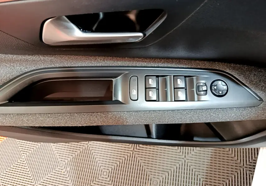 Gros plan sur la commande des vitres et rétroviseurs côté gauche de la porte intérieure noire du Peugeot 3008 blanc 2020.