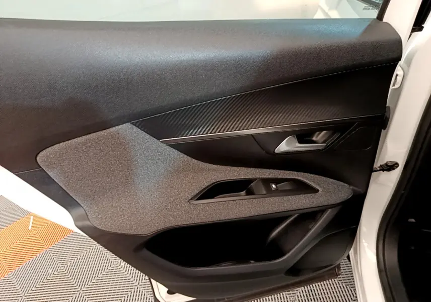 Gros plan sur la porte avant gauche blanche d'un Peugeot 3008 2020, avec garniture noire et inserts effet carbone.