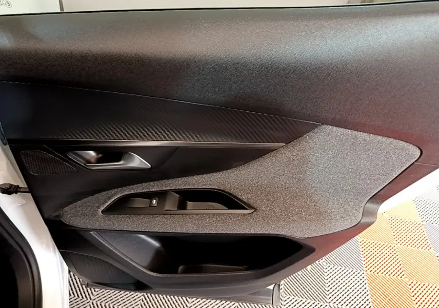 Porte intérieure côté gauche du Peugeot 3008 blanc, avec habillage noir et gris texturé et poignée argentée.