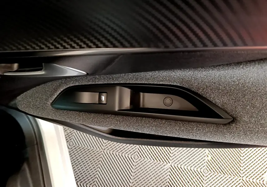 Gros plan sur la commande de lève-vitre côté conducteur, avec garniture tissu gris et poignée argentée du Peugeot 3008 blanc.