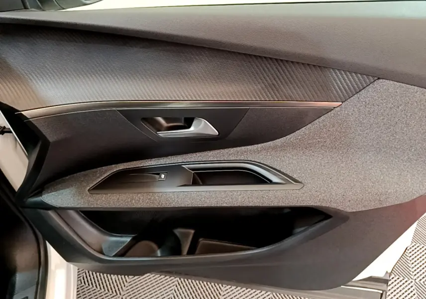Vue rapprochée de la porte avant gauche du Peugeot 3008 blanc, mettant en valeur les textures et la poignée intérieure.