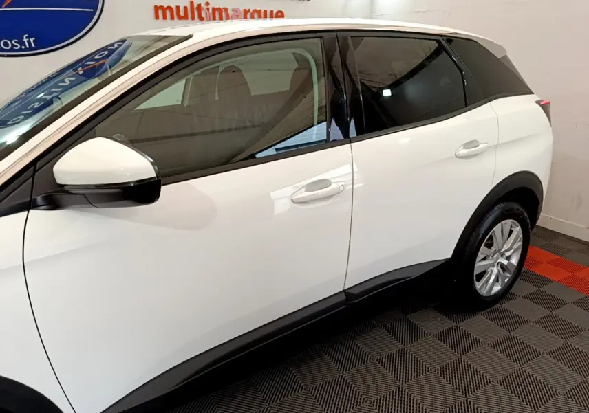 Profil côté gauche du Peugeot 3008 blanc avec vitres teintées et jantes alliage visibles en intérieur showroom.
