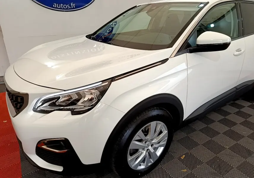 Vue 3/4 avant droit d'un Peugeot 3008 blanc avec phares LED et jantes alliage dans un showroom.