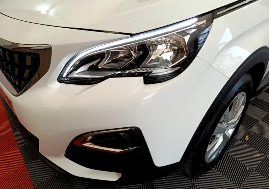 Gros plan sur l'avant droit blanc du Peugeot 3008 2020, mettant en valeur le phare et la calandre distinctive.
