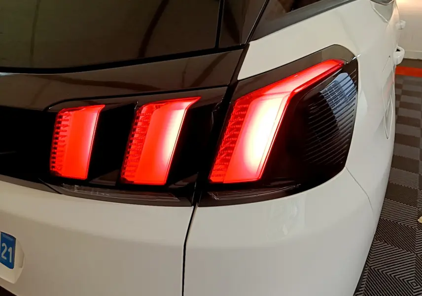 Gros plan sur le feu arrière droit rouge vif du Peugeot 3008 blanc, soulignant le contraste avec le toit noir.