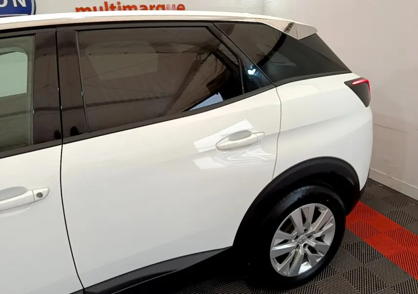 Vue latérale droite du Peugeot 3008 blanc avec vitres teintées et jantes alliage, arrière du SUV en intérieur showroom.