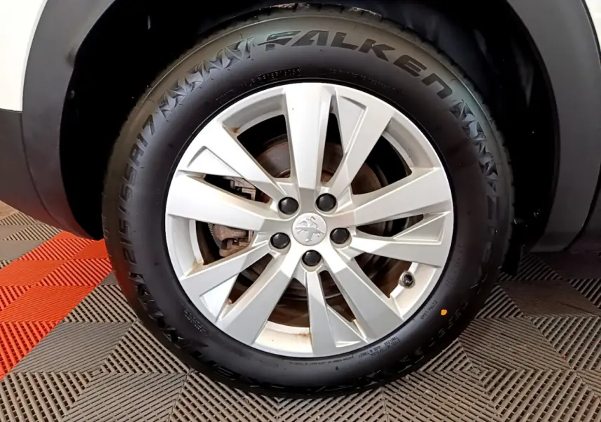 Gros plan sur la roue avant droite du Peugeot 3008 blanc, mettant en valeur la jante alliage et le pneu Falken.