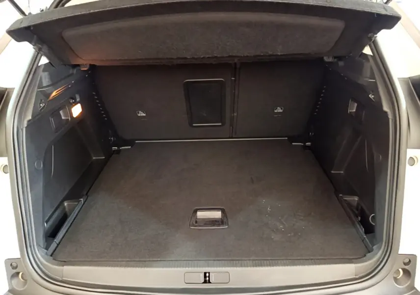 Coffre ouvert vu de l'arrière d'un Peugeot 3008 blanc, espace de chargement propre et bien éclairé.