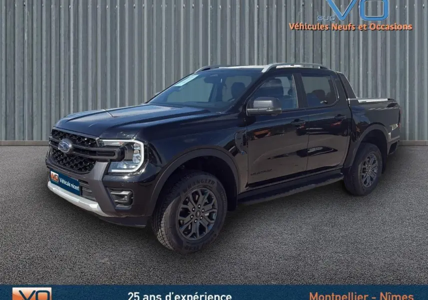 Ford Ranger Wildtrak noir en 3/4 avant droit, avec barres de toit, marchepieds et jantes alliage 18 pouces visibles.