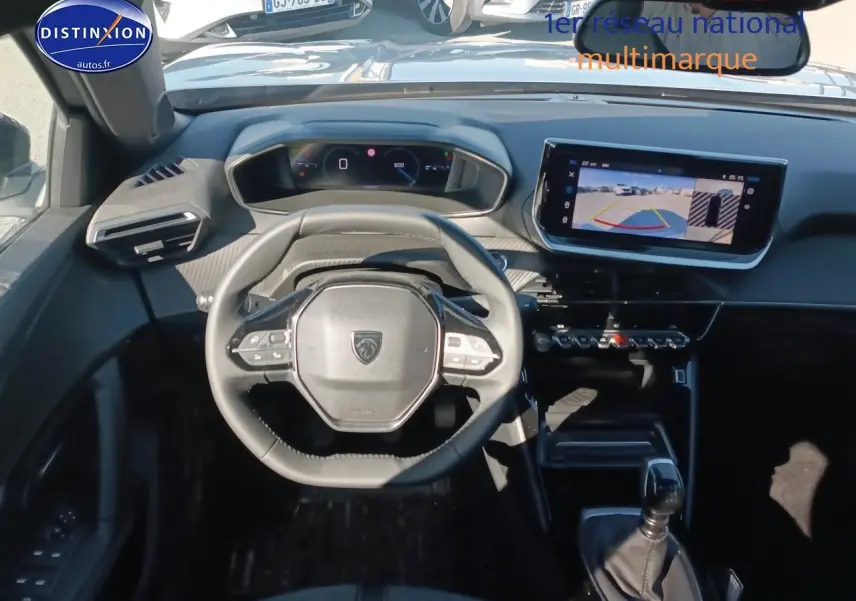 Vue intérieure frontale du poste de conduite du Peugeot 2008 gris, avec volant multifonction et écran tactile affichant la caméra de recul.