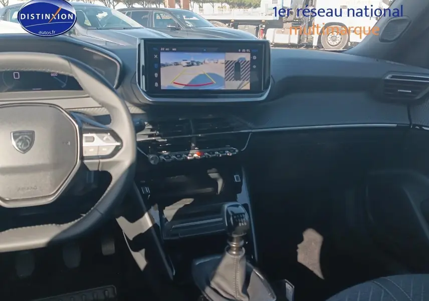 Intérieur de la Peugeot 2008 2025 en gris, vue du poste de conduite avec écran tactile et levier de vitesse manuel.
