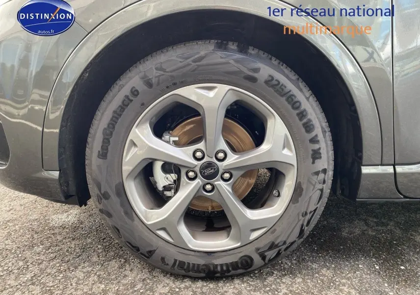 Gros plan sur la roue avant droite en jante alu gris d’un Ford Kuga gris Magnetic Fashion Métallisée.