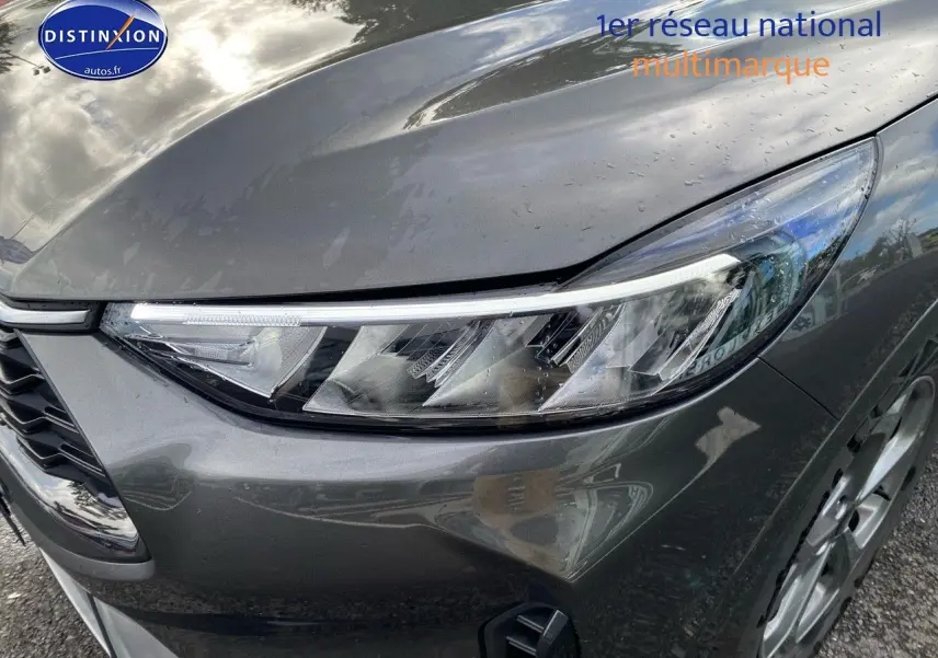 Gros plan sur l'avant droit gris métallisé du Ford Kuga 2025, mettant en valeur le phare LED et la roue galette.