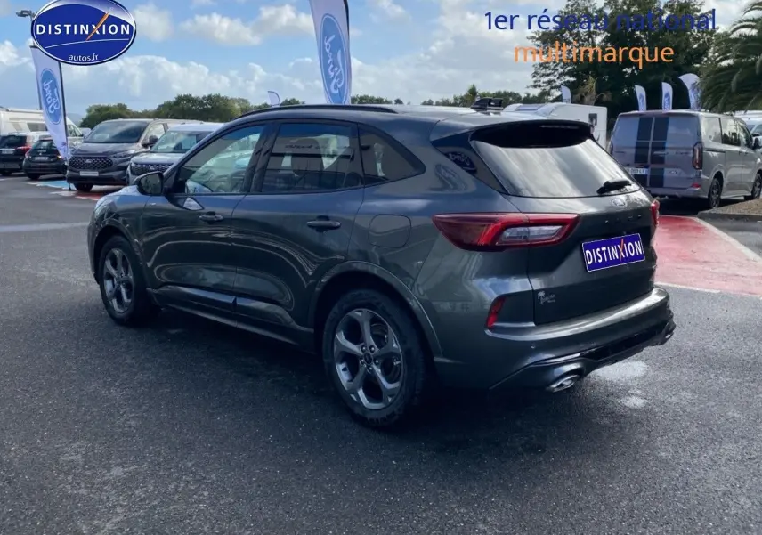 Ford Kuga gris Magnetic Fashion vue 3/4 arrière droit, avec jantes alu et feux arrière LED dans un parking extérieur.