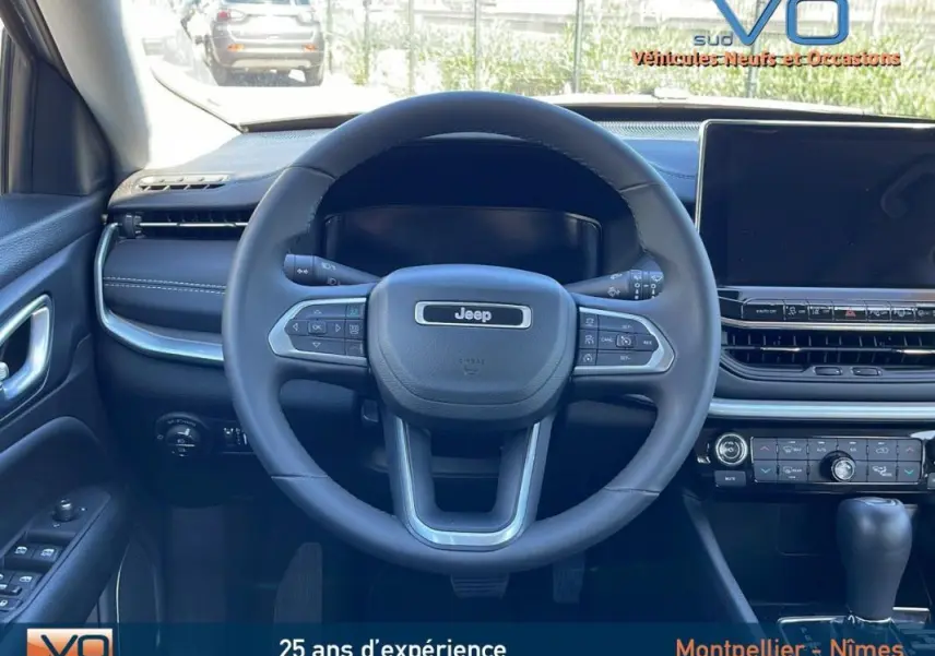 Vue intérieure centrée sur le volant Jeep noir et tableau de bord avec écran tactile du Compass blanc 2024.