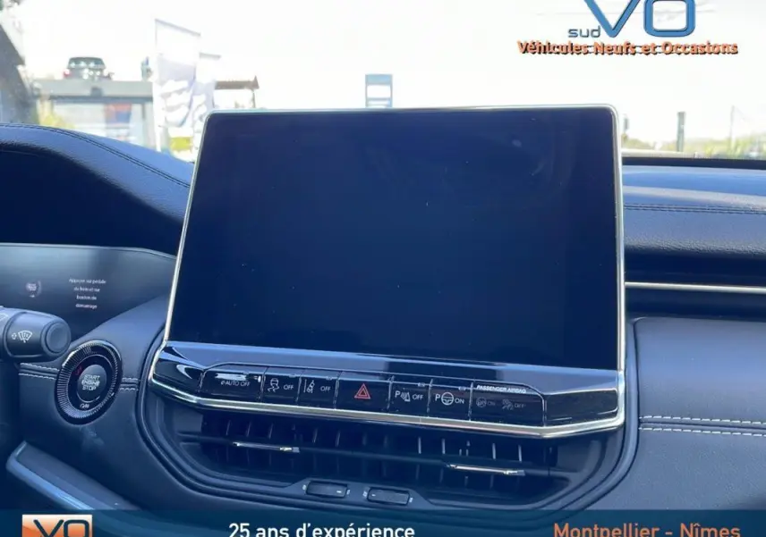 Vue rapprochée de l'écran tactile et des commandes du tableau de bord du Jeep Compass blanc 2024 en intérieur.