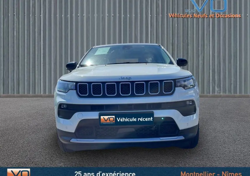 Vue frontale d'un Jeep Compass blanc 2024 avec calandre distinctive et phares LED allumés sur fond neutre.