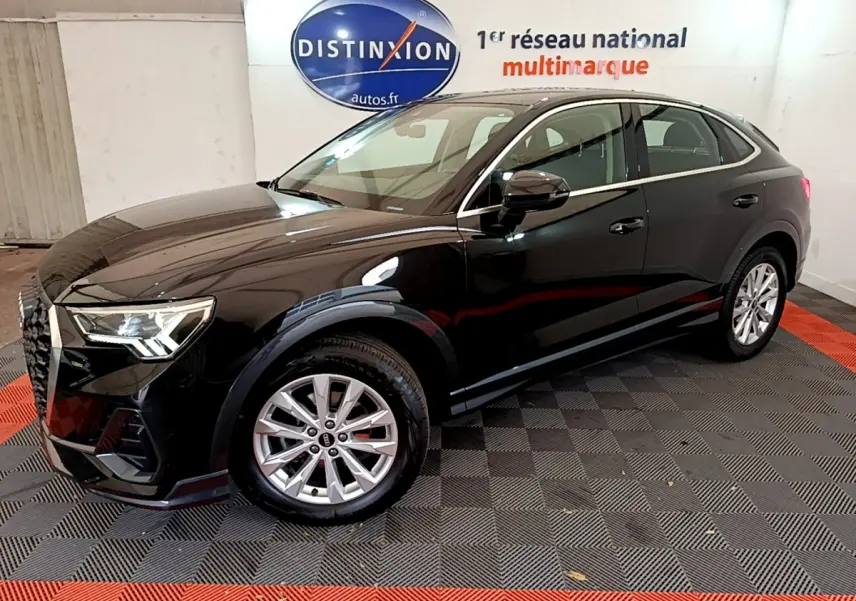 Audi Q3 Sportback noir vu de profil côté gauche dans un showroom avec sol à damiers gris et rouge