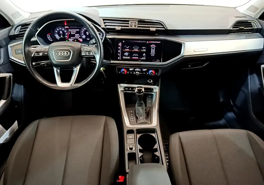 Intérieur Audi Q3 Sportback 2021 vu de face, tableau de bord noir avec écran tactile et volant cuir multifonctions.