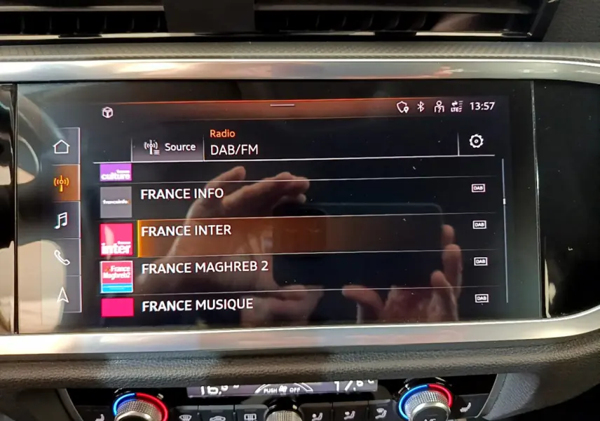 Écran tactile central de l'Audi Q3 Sportback 35 TFSI noir, affichant les stations radio DAB/FM en intérieur.