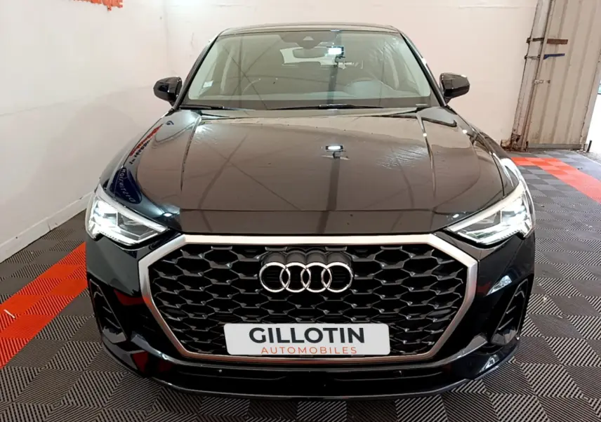 Audi Q3 Sportback noir vue de face mettant en valeur sa calandre hexagonale et ses phares LED allumés.