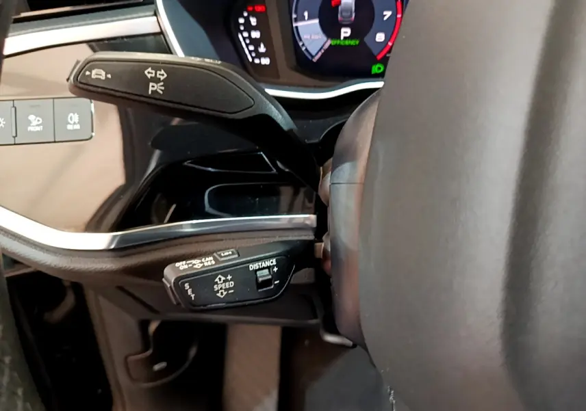 Gros plan sur les commandes au volant à gauche de l'Audi Q3 Sportback 35 TFSI noir, avec tableau de bord numérique visible.