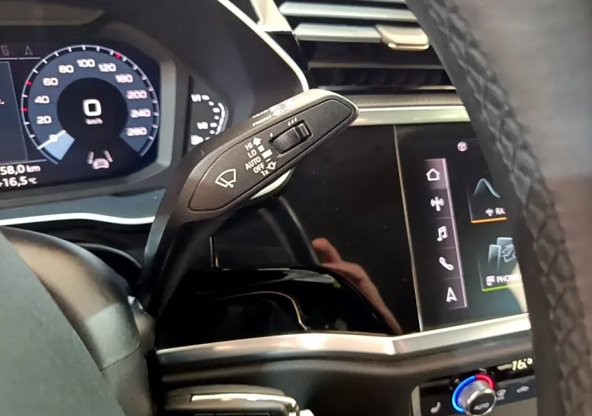 Gros plan sur la commande d'essuie-glace et le tableau de bord numérique d'un Audi Q3 Sportback noir, intérieur moderne.