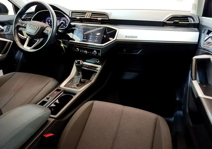 Intérieur Audi Q3 Sportback 2021 vu côté conducteur, tableau de bord noir avec écran tactile et volant cuir multifonctions.