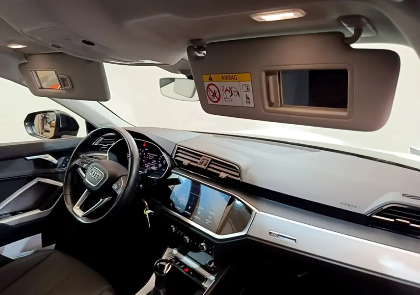 Intérieur de l'Audi Q3 Sportback 2021 vu côté conducteur, tableau de bord moderne avec écran tactile et volant cuir noir.