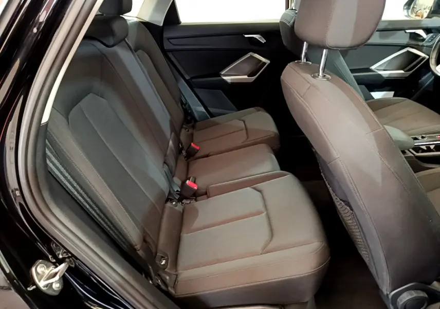 Vue intérieure côté gauche sur la banquette arrière et les sièges avant noirs de l'Audi Q3 Sportback 2021.