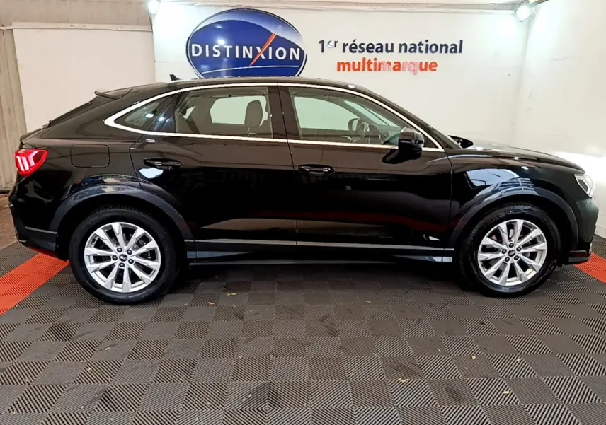 Audi Q3 Sportback noir vue de profil côté gauche, avec jantes argentées et feux arrière LED allumés.