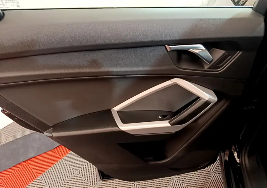 Gros plan sur la porte intérieure côté droit noire de l'Audi Q3 Sportback 2021 avec poignée argentée et commande de vitre.