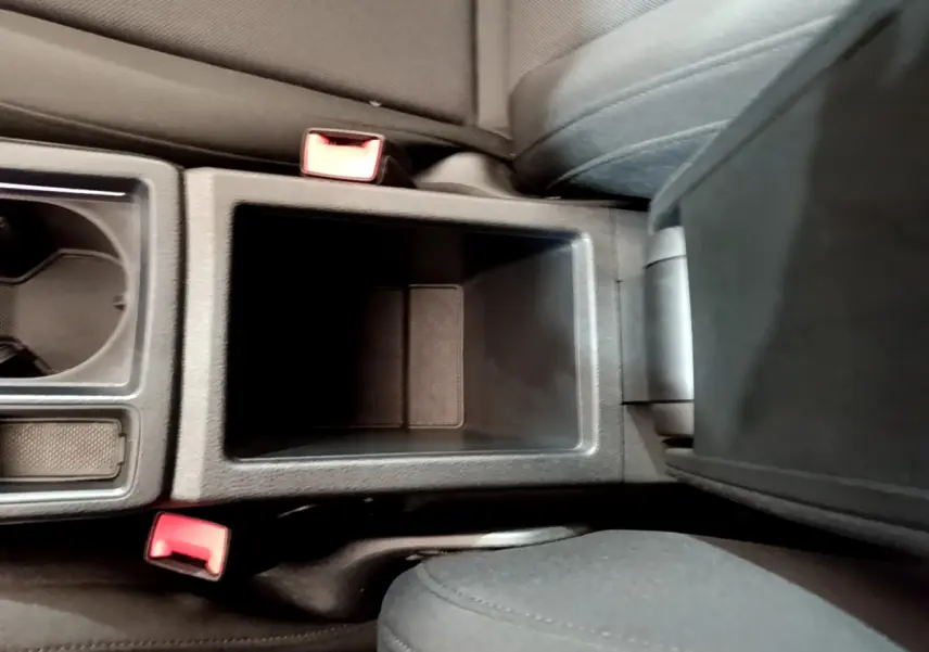 Vue plongeante sur la console centrale noire de l'Audi Q3 Sportback 2021, avec porte-gobelets et accoudoir ouvert.