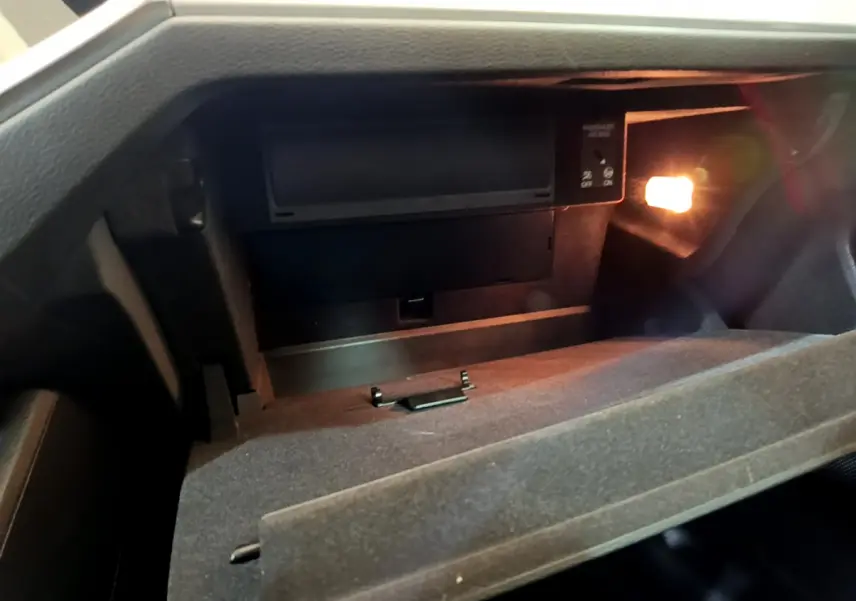 Intérieur de la boîte à gants ouverte de l'Audi Q3 Sportback noir, éclairée par une petite lampe intérieure.