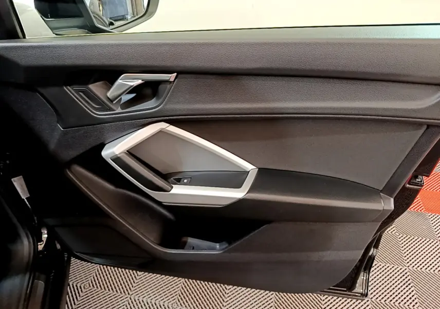 Intérieur noir de la porte côté gauche de l'Audi Q3 Sportback 2021 avec poignée argentée et commandes de fenêtre.
