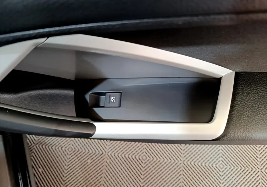 Détail de la commande d'ouverture du coffre sur la porte intérieure côté gauche d'un Audi Q3 Sportback noir 2021.
