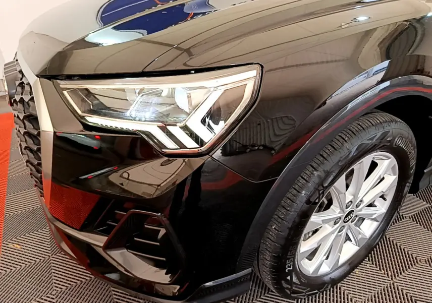 Gros plan sur l'avant droit noir brillant de l'Audi Q3 Sportback 2021, mettant en valeur son phare LED et la roue.