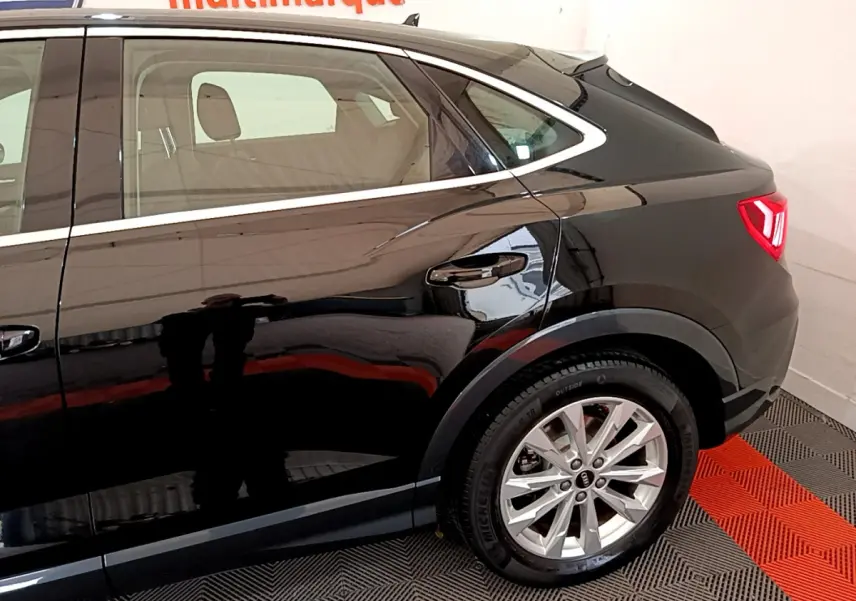 Vue latérale droite de l'Audi Q3 Sportback noir, mettant en valeur la roue arrière et la ligne de toit plongeante.
