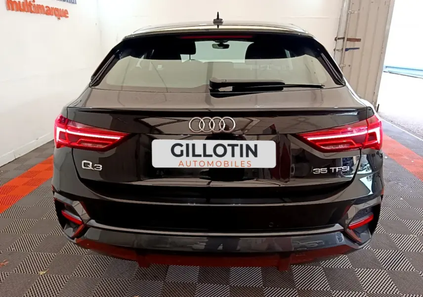 Vue arrière d'un Audi Q3 Sportback noir 35 TFSI avec feux LED allumés dans un garage fermé.