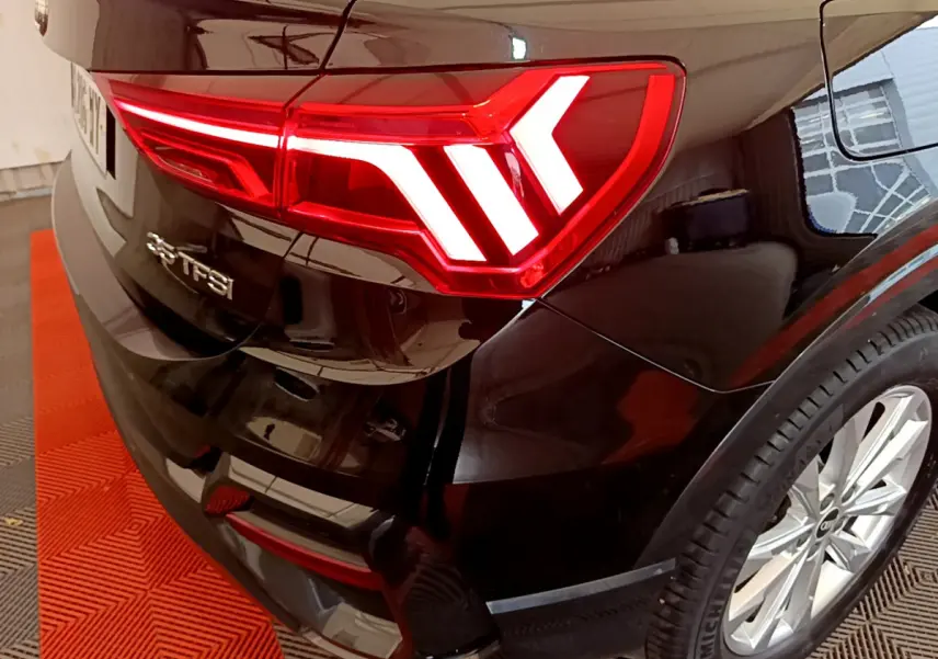 Gros plan sur le feu arrière droit rouge d'un Audi Q3 Sportback noir, avec logo 35 TFSI visible sur le coffre.