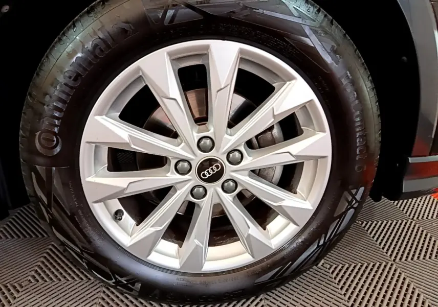 Gros plan sur la roue avant droite d'un Audi Q3 Sportback noir, mettant en valeur la jante en alliage argentée à 10 branches.