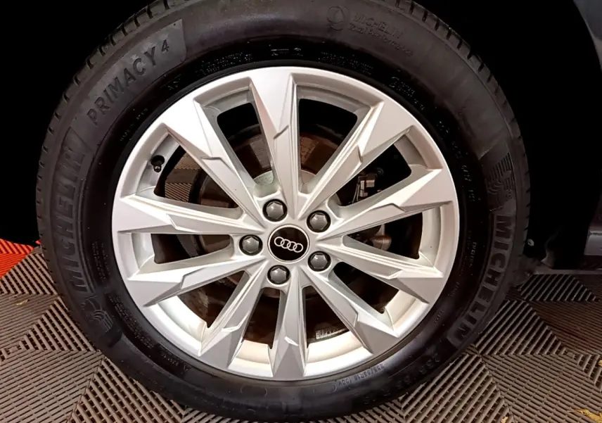 Gros plan sur la jante argentée de l'Audi Q3 Sportback noir, mettant en valeur le logo Audi central.