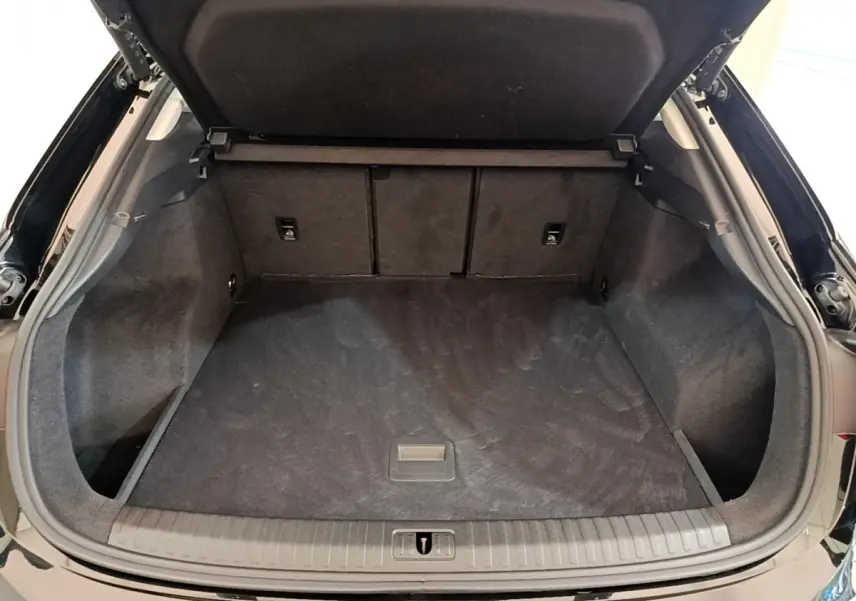 Coffre ouvert vu de l'arrière d'un Audi Q3 Sportback noir, espace de chargement propre et spacieux.