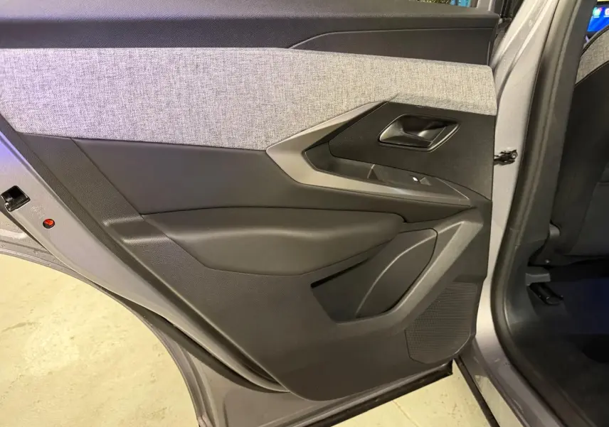 Vue intérieure de la porte arrière gauche grise du Peugeot 3008 1.2 Hybrid 136 Allure avec garniture tissu gris et plastique noir.