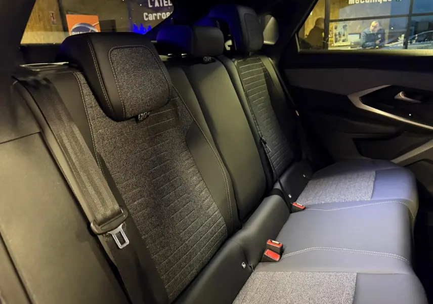 Vue intérieure des sièges arrière en tissu gris et noir du Peugeot 3008 1.2 Hybrid 136 Allure, ambiance tamisée.