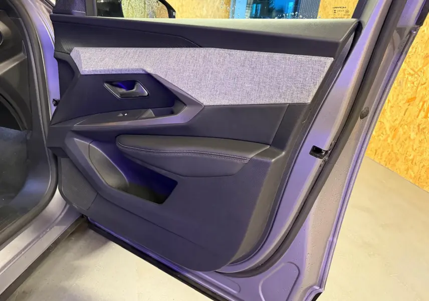 Vue rapprochée de la porte avant gauche gris métallisé du Peugeot 3008 1.2 Hybrid 136 Allure avec habillage tissu et cuir noir.