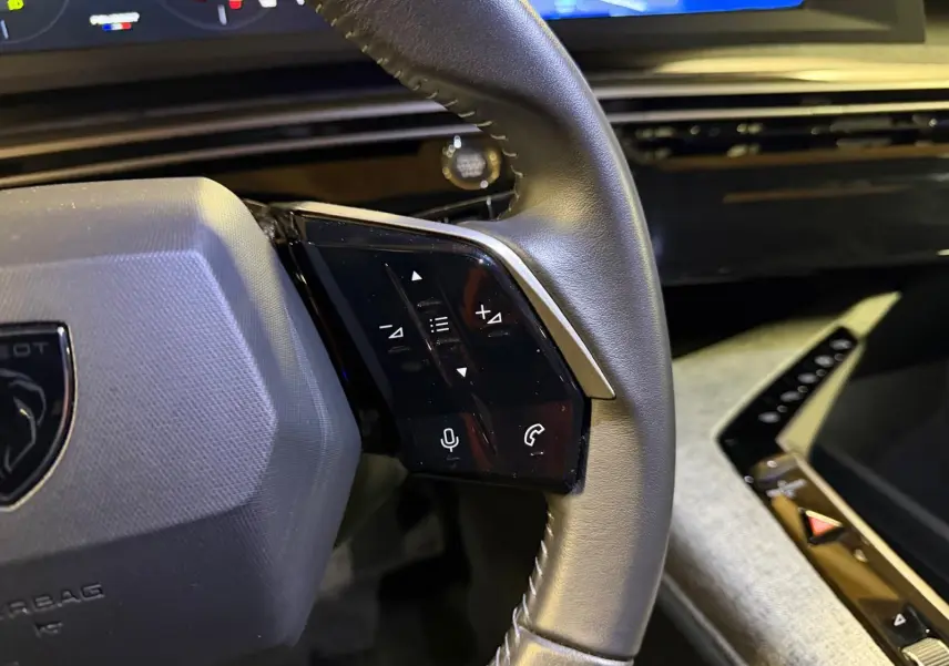 Gros plan sur le volant cuir noir du Peugeot 3008 1.2 Hybrid 136 Allure avec commandes vocales et téléphone intégrées.