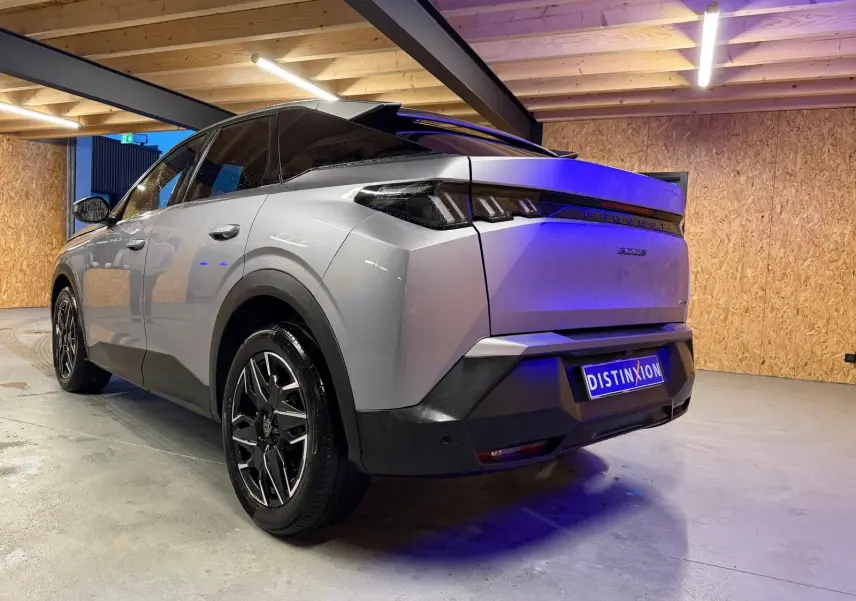 Vue 3/4 arrière droite du Peugeot 3008 gris hybride 2025 avec toit noir et jantes alliage distinctives.